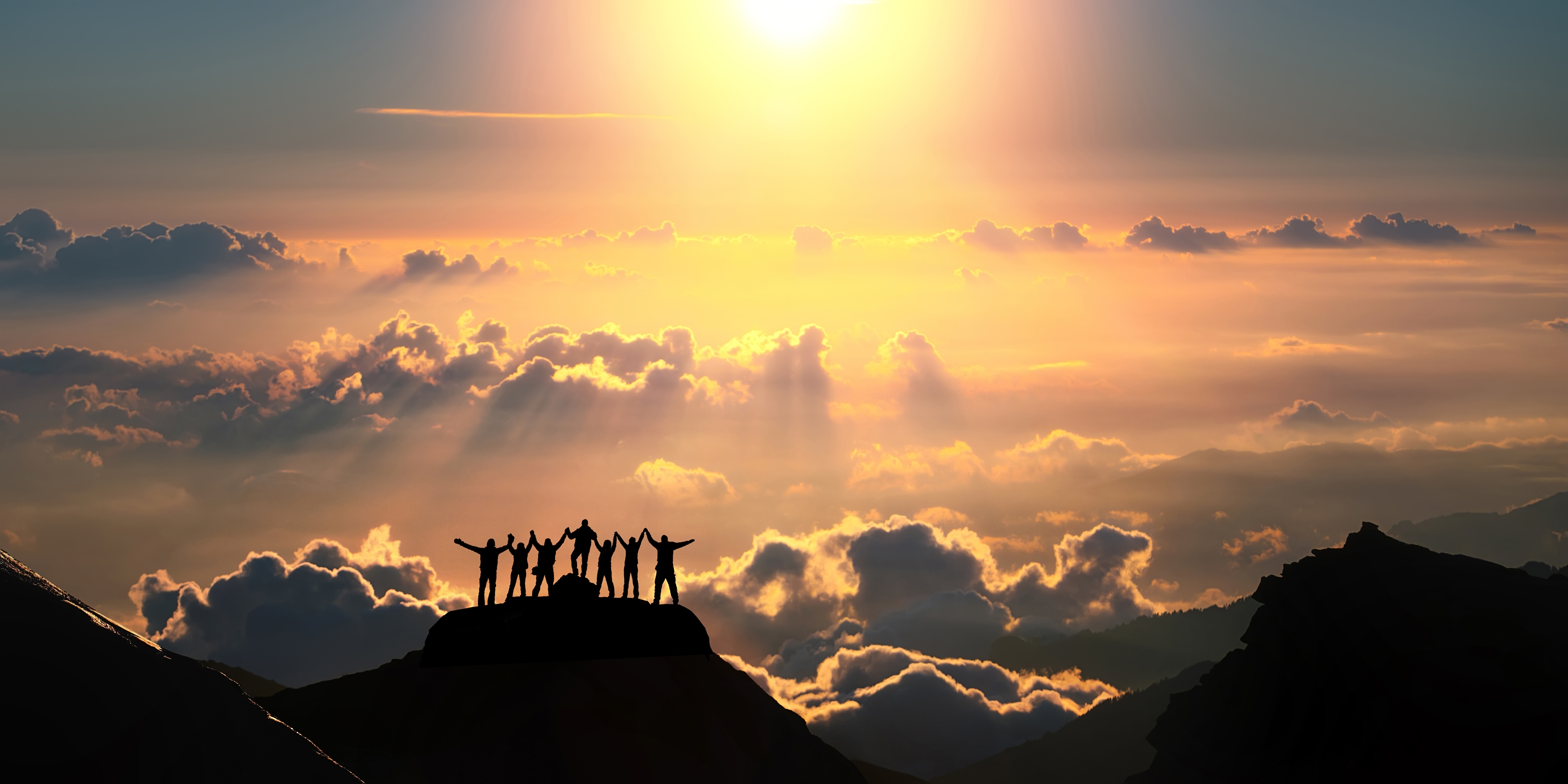 Team of people standing together on top of a mountain